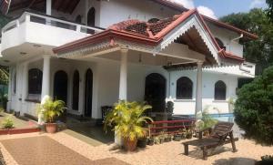 a white house with a bench in front of it at Kingz and Queenz - Negombo in Negombo