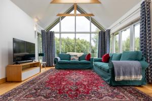 a living room with two green couches and a tv at Wildings Ardcavan in Wexford