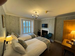 una camera d'albergo con tre letti e un camino di Brunswick House a Middleton-in-Teesdale