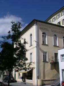 un edificio esterno di un hotel con un albero di fronte di Hotel Quellenhof a Scuol