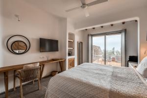 a bedroom with a bed and a desk and a television at Alissachni Mykonos in Psarou