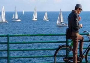 a man on a bike looking at boats in the water at Venere B&B in Catania