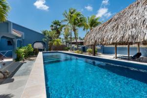 a swimming pool at a resort with a thatched roof at Blue Bonaire by Boutique Bonaire Unique Resorts in Kralendijk