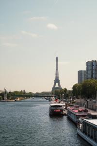 - une vue sur la tour Eiffel depuis une rivière avec des bateaux dans l'établissement Veeve - Soothing Encounter, à Paris