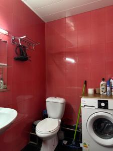 uma casa de banho vermelha com um WC e uma máquina de lavar roupa em Nina’s Sweet Home em Tbilisi