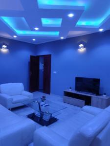 - un salon avec un canapé, une télévision et des lumières bleues dans l'établissement HOTEL APPART B4U, à Yaoundé