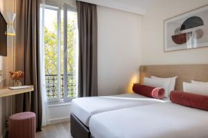 a hotel room with two beds and a window at Le Bailli in Paris