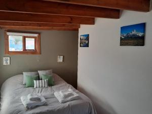 a bed in a bedroom with green pillows on it at Cerro Rosado in El Chalten