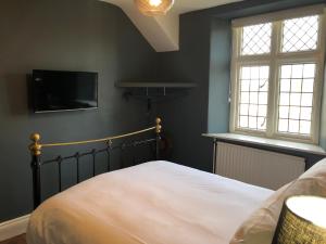 a bedroom with a bed and a flat screen tv at The Wheatsheaf at Beetham in Sandside