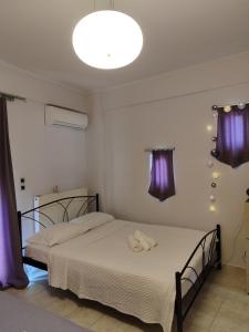 sypialnia z 2 łóżkami i fioletowymi zasłonami w obiekcie Vasiliki house 1 w mieście Vartholomión