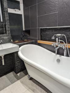 a bathroom with a white tub and a sink at Waves of Memories Rhos on Sea in Llandrillo-yn-Rhôs