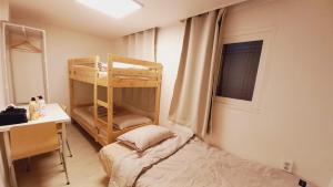 Cette petite chambre comprend des lits superposés et un bureau. dans l'établissement G Yongsan Inn, à Séoul