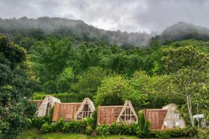 a group of wicker cottages in front of a mountain at บ้านธารหมอก แอท สะปัน in Ban Huai Ti