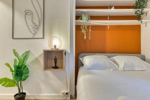 a bedroom with a bed and a plant and a lamp at Ceylan - bel F2 à Rouen in Rouen