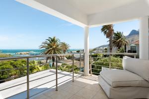a balcony with a couch and palm trees and the ocean at 58 Kreef Lane in Cape Town