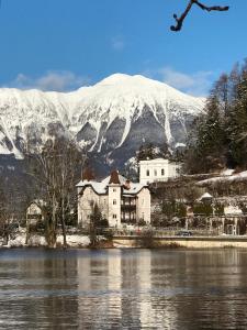 un edificio junto a un cuerpo de agua con una montaña cubierta de nieve en Adora Luxury Hotel, en Bled