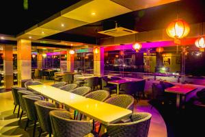 a restaurant with tables and chairs and purple lights at Fu Wang Dominous Resort in Cox's Bazar