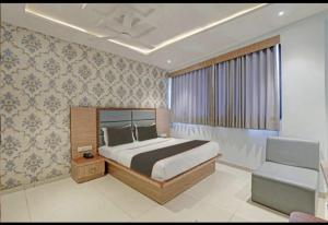 a bedroom with a king sized bed and a chair at Hotel Privilege View in Ahmedabad