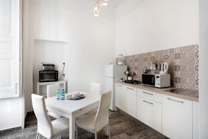 a white kitchen with a white table and chairs at Appartamento Al Corso in Salerno