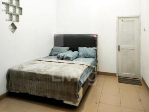Ce lit se trouve dans un dortoir doté d'un mur blanc. dans l'établissement Guest House Syariah Bunga Intan RedPartner, à Metro