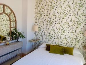 1 dormitorio con cama blanca y papel pintado con motivos florales en Villa Martiniano, en Campano