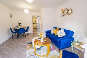 ein Wohnzimmer mit einem blauen Sofa und einem Tisch in der Unterkunft Immaculate 4-Bed House in Kings Norton in Birmingham