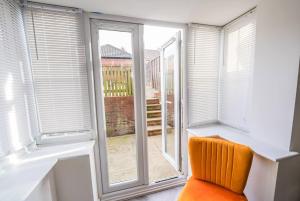 an orange chair sitting in front of a window at Immaculate 4-Bed House in Kings Norton in Birmingham