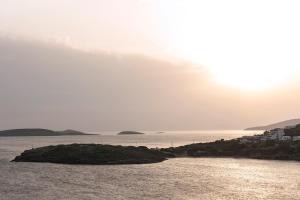 un'isola in acqua con il sole sullo sfondo di Villa Fiamegou Andros a Mpatsi (Batsi)