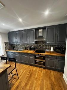 a kitchen with black cabinets and a wooden floor at High Wycombe Centre- 2 bed flat in Buckinghamshire