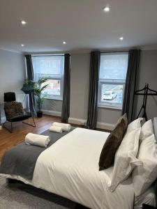 a bedroom with a large bed and two windows at High Wycombe Centre- 2 bed flat in Buckinghamshire