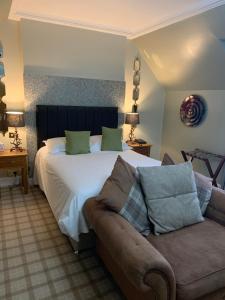 a bedroom with a large bed and a couch at The Powfoot Hotel, Annan in Annan