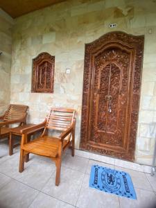 2 chaises en bois assises devant une porte dans l'établissement Volcano Living, à Kintamani