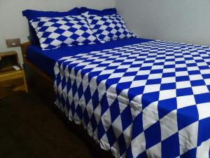 een bed met een blauwe en witte geruite deken bij Mixtech Vacation Home -MVH in Sunyani
