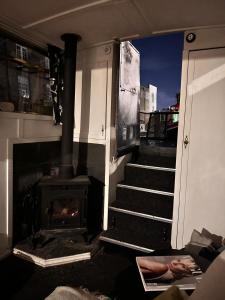 a room with a fireplace and stairs with a stove at Narrow Boat moored in London in London