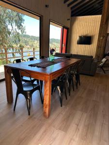 una gran mesa de madera con sillas y un sofá en Cabañas Wildki Lodge Vichuquen, en Curicó