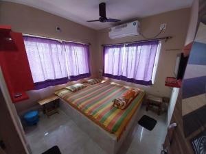 a bedroom with a bed and two windows at Home stay world in Bolpur