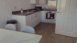 a kitchen with white cabinets and a table with chairs at Impeccable 3-Bed House in Northampton in Northampton