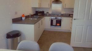 a kitchen with white cabinets and a counter with chairs at Impeccable 3-Bed House in Northampton in Northampton