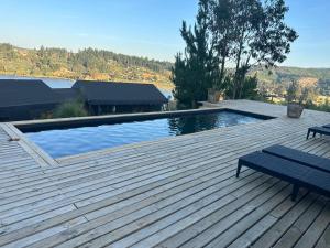 a swimming pool on a wooden deck with a bench at Cabañas Wildki Lodge Vichuquen in Curicó