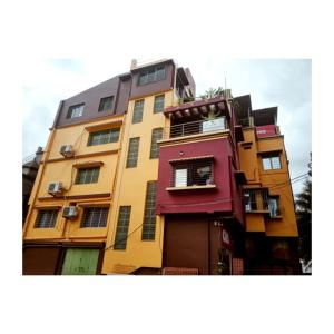 a tall yellow and red building with windows at Home stay world in Bolpur