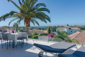 a patio with a table and chairs and a palm tree at Villa Near Beach in Marbella with Heated Pool in Marbella