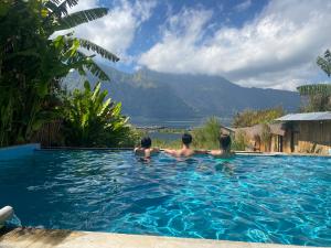 Tres personas en una piscina con montañas en el fondo en Volcano Living en Kintamani
