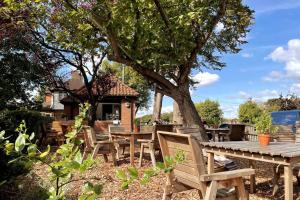 a group of wooden tables and chairs under a tree at Spacious 3 bedroom house in heart of Hampton Court in East Molesey