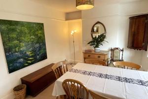 a dining room with a white table and a painting at Spacious 3 bedroom house in heart of Hampton Court in East Molesey