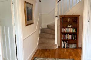 a stairway with a book shelf and stairs with books at Spacious 3 bedroom house in heart of Hampton Court in East Molesey