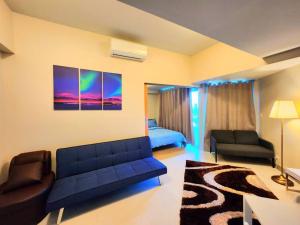 sala de estar con sofá azul y cama en BGC Cosy Spacious 1BR Uptown Parksuites with Balcony City View, en Manila