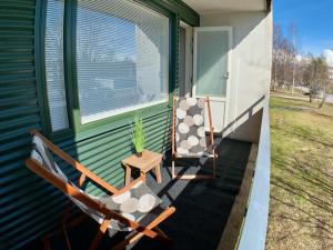 two chairs and a table on the porch of a house at Kaupunkikoti in Kemi