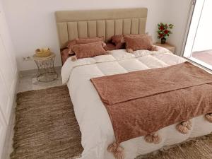 um quarto com uma cama grande e almofadas castanhas em Le cocon de Mariem à El Kantaoui em Port El Kantaoui