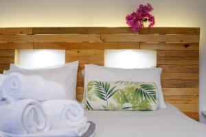 a bed with white pillows and palm trees at Villa Nidito Santorini in Vlychada Beach