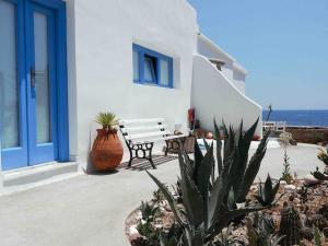 una panchina seduta di fronte a un edificio bianco di Villa Nidito Santorini a Vlychada Beach